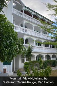 een groot wit gebouw met bomen ervoor bij Mountain View Hotel and Bar Restaurant in Cap-Haïtien