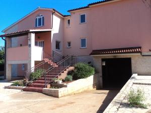 una gran casa rosa con garaje y escaleras en Apartments Vera, en Ližnjan