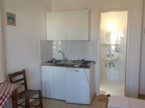a kitchen with white cabinets and a sink and a bathroom at Rania Apartments in Antiparos Town +49 photos