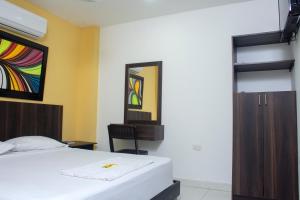 a bedroom with a bed and a desk and a mirror at Hotel Gixael in Santa Marta