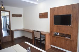 a living room with a television and a desk with a chair at Hotel Apple Valley in Kodaikānāl