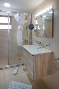 uma casa de banho com um lavatório e um chuveiro com um espelho. em Triple A Hotel Suites em Amã