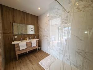 a bathroom with a sink and a glass shower at La suite de la route des chateaux in Arsac