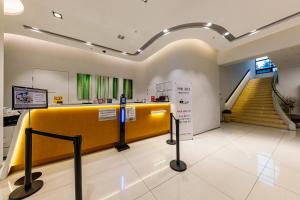 a lobby with a staircase and a yellow wall at Crown Hotel Changwon in Changwon
