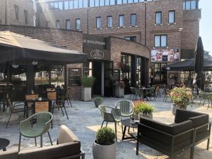 un patio avec des chaises et des tables en face d'un bâtiment dans l'établissement Holiday Inn Hasselt, an IHG Hotel, à Hasselt