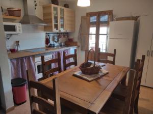 una cucina con tavolo in legno, sedie e frigorifero di Casas Los Carabos La Cueva a Letur