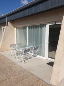 una mesa de cristal y 2 sillas en el patio en Clos du Béron- Appartement meublé de tourisme, en Cappelle-en-Pévèle