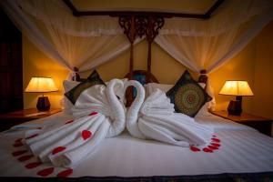Dos cisnes hechos de toallas en una cama en Sunny Palms Beach Bungalows, en Uroa