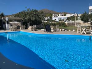 a large blue swimming pool with tables and chairs at Hotel Anezina in Drios