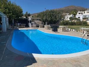 a large blue swimming pool with tables and chairs at Hotel Anezina in Drios