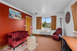 Americana Inn Motel في سووث سان فرانسيسكو: غرفة معيشة مع أريكة حمراء وطاولة