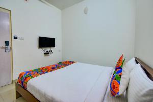 a white room with a bed with a tv on the wall at FabExpress PAS Residency - Nr Marina Beach in Chennai