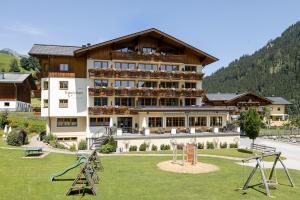 a large building with a playground in front of it at Hotel Roslehen in Grossarl