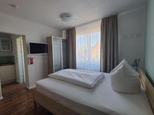 a bedroom with a white bed with a window at Haus Achtern Diek in erster Reihe am Meer in Fehmarn
