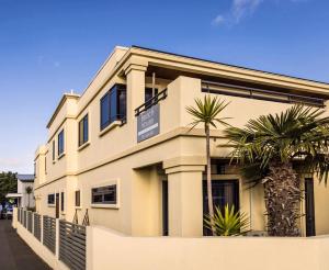 a white building with palm trees in front of it at Beach House Studios in Napier