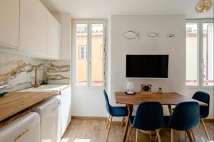 a kitchen with a wooden table and blue chairs at Appartement le Quai du Port Cassis parking clim in Cassis