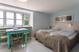 two beds in a room with a desk and two windows at Rødvig Kro og Badehotel in Rødvig