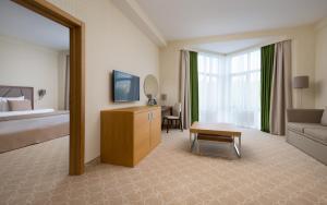 a hotel room with a bedroom with a bed and a couch at Green Resort Hotel and SPA in Kislovodsk