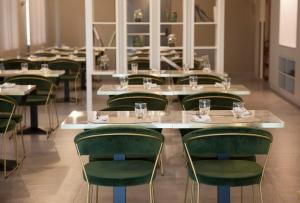 una fila de mesas en una habitación con sillas verdes en Lo Scoiattolo Piedmont Bike Hotel, en Pralormo