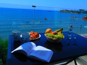 a table with an open book and a bowl of fruit at AKTIS MAKRIGIALOS LUXURY APTS in Makry Gialos