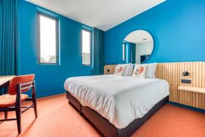 um quarto azul com uma cama, uma mesa e um espelho em Mah Hotel em Saint-Ghislain