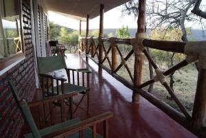 a porch with chairs and tables on a house at African Sunrise Lodge and Campsite in Mto wa Mbu