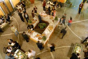 a crowd of people standing around a table with food at City Hotel in Casoria