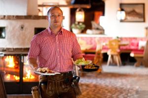 un hombre sosteniendo un plato de comida en un restaurante en Winklalm en Flachau