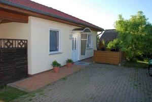 ein weißes Haus mit einem Tor und einer Auffahrt in der Unterkunft Ferienhaus Guenter in Gager