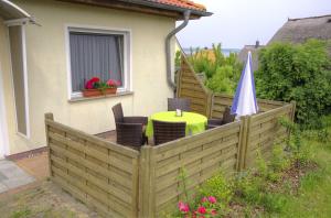 einen Holzzaun mit einem Tisch und einem Regenschirm in der Unterkunft Ferienhaus Guenter in Gager