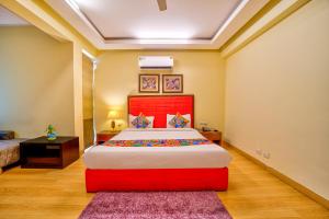 1 dormitorio con 1 cama grande y cabecero rojo en FabHotel Rivlet, en Gurgaon