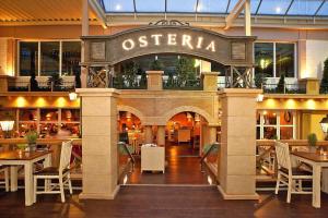 a restaurant with tables and chairs and a sign that reads osteria at Studios im Ferien- und Freizeitpark Weissenhäuser Strand, Weissenhäuser Strand in Weissenhäuser Strand