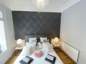 a bedroom with a bed with white pillows at Le Clovis Suites Spa Sauna in Reims