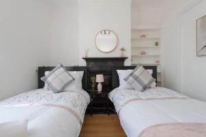 two beds in a room with white walls and a mirror at The Mount 3 Bedroom Relaxation Home in Chatham