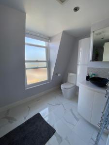 a bathroom with a toilet and a sink and a window at 3 bed Apartment in Colliers Wood in London