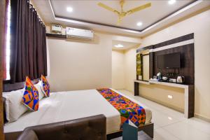 a hotel room with a bed and a tv at FabHotel Rotano Suites Yelahanka in Bangalore