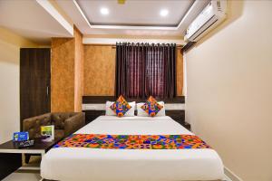 a bedroom with a large bed and a desk at FabHotel Rotano Suites Yelahanka in Bangalore
