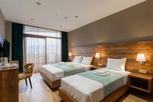 a hotel room with two beds and a television at Cozy Loft Hotel in Batumi