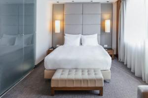 a bedroom with a large white bed and a bench at Belgrade Art Hotel, a member of Radisson Individuals in Belgrade +38 photos