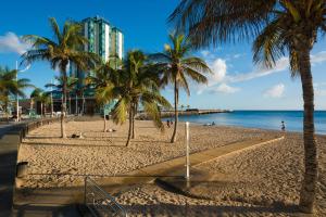 a beach with palm trees and a building at Apartamento Luna in Arrecife