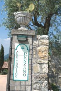 a sign on a stone wall with a vase on top at Agriturismo Renzano garden apartments in Salò