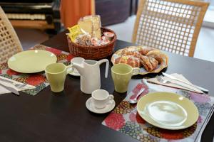 una mesa con platos y tazas y una cesta de bollería en Residenza Pizzofalcone, en Nápoles