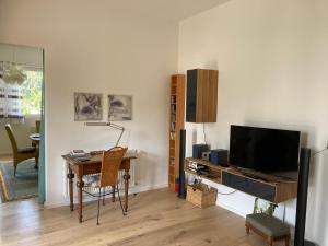 een woonkamer met een bureau en een televisie bij Gästewohnung Mosbach in Mosbach