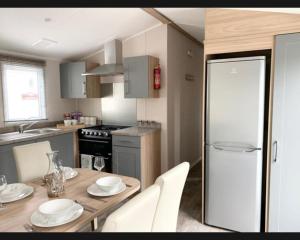 a kitchen with a wooden table and a white refrigerator at Exotic 3-Bed Caravan at Newquay Holiday Park in Newquay
