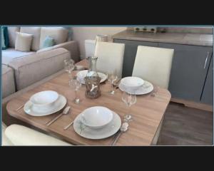 a wooden table with plates and wine glasses on it at Exotic 3-Bed Caravan at Newquay Holiday Park in Newquay