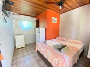 1 dormitorio con 2 camas y pared de color naranja en Pousada Tia Maria, en Paranaguá