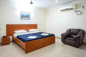a bed and a chair in a room at Hotel TamilNadu -Trichy in Tiruchchirāppalli