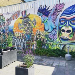 a wall covered in graffiti with a mural oficans at HOTEL N Hostel Malmö City in Malmö