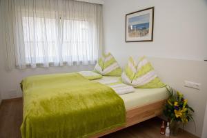 1 cama con manta verde y almohadas en Villa Mayr, en Villach