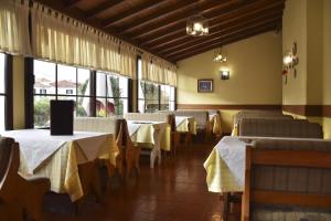 uma sala de jantar com mesas, cadeiras e janelas em Hotel O Colmo em Santana